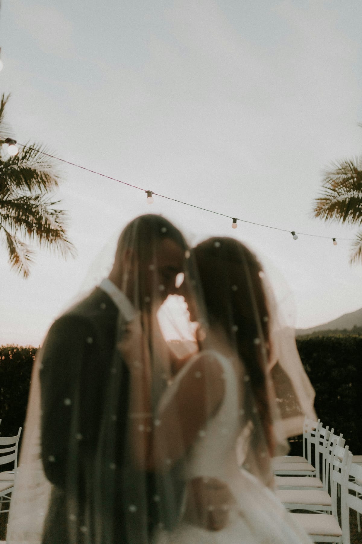 A couple beneath festoon lights at an evening celebration